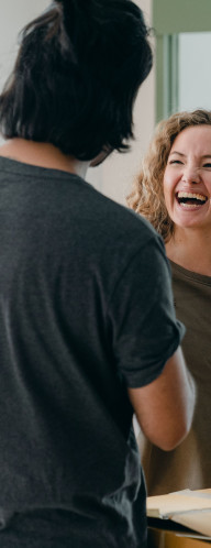 A young man and woman between moving boxes, laughing