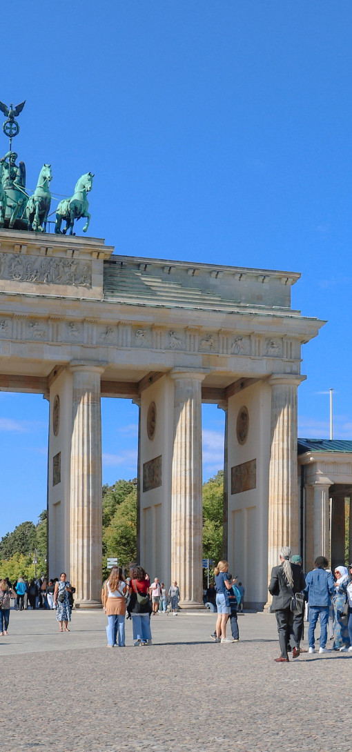 The Brandenburg Gate in Berlin, with people standing and walking in the area