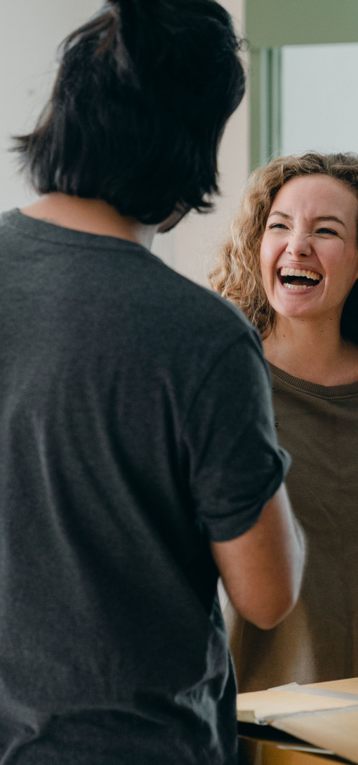 A young man and woman between moving boxes, laughing