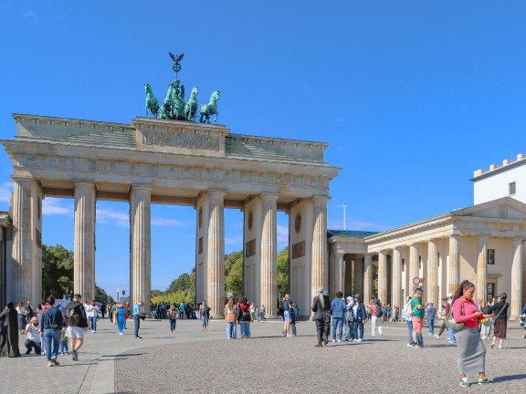 The Brandenburg Gate in Berlin, with people standing and walking in the area