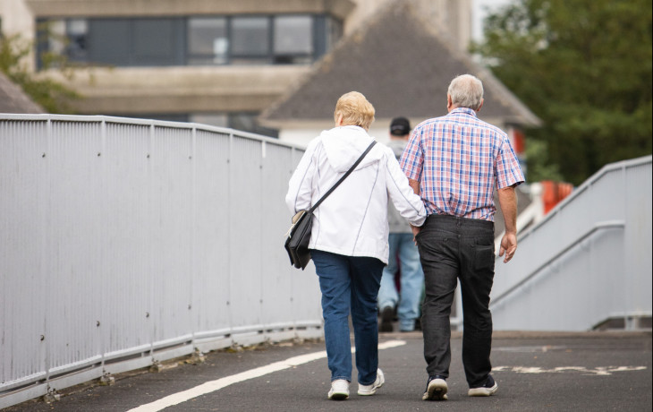 two older people walking arm in arm