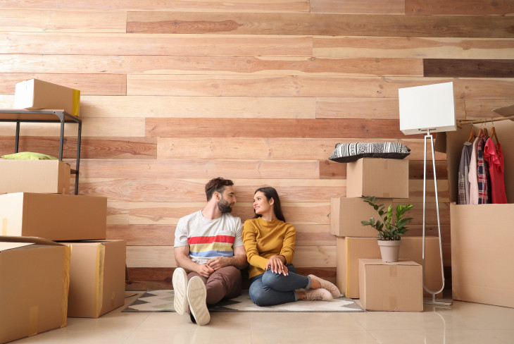 Couple sitting on a rug surrounded by boxes