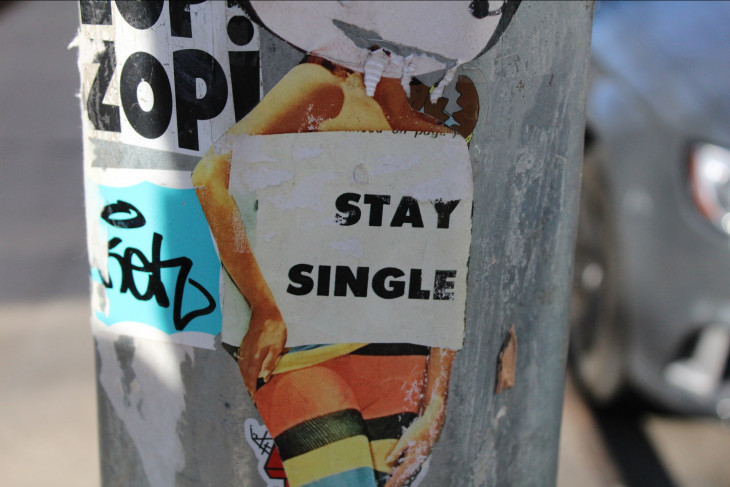 Sticker on lamp post that says 'stay single'