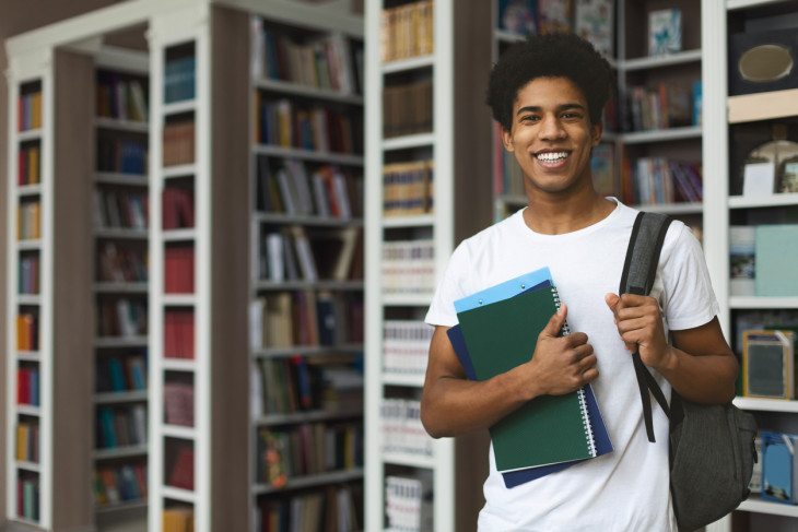 Black male student posing in campus library