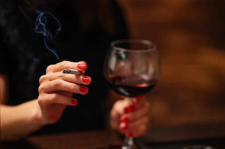 Woman holding wine and cigarrete 