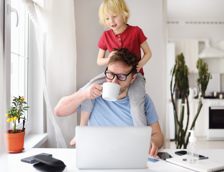 Man working from home with laptop during quarantine. Home office and parenthood at same time.