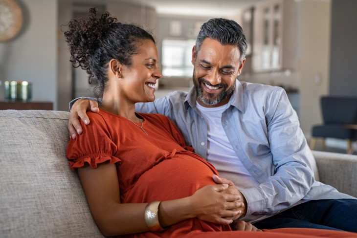 Mid adult couple expecting a baby while husband caresses the belly of his pregnant woman