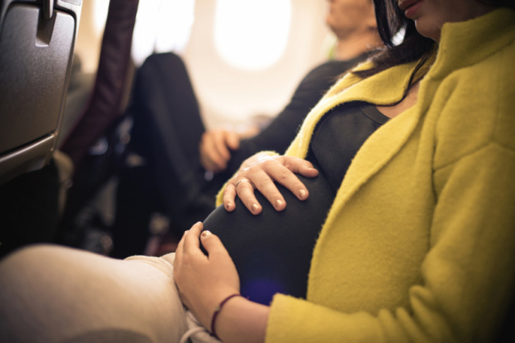 Pregnant woman traveling with airplane. Close up.