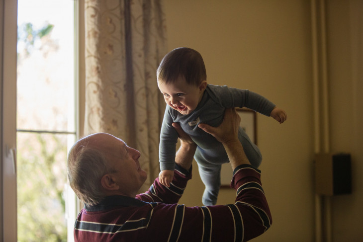 Grandfather raising baby into the air