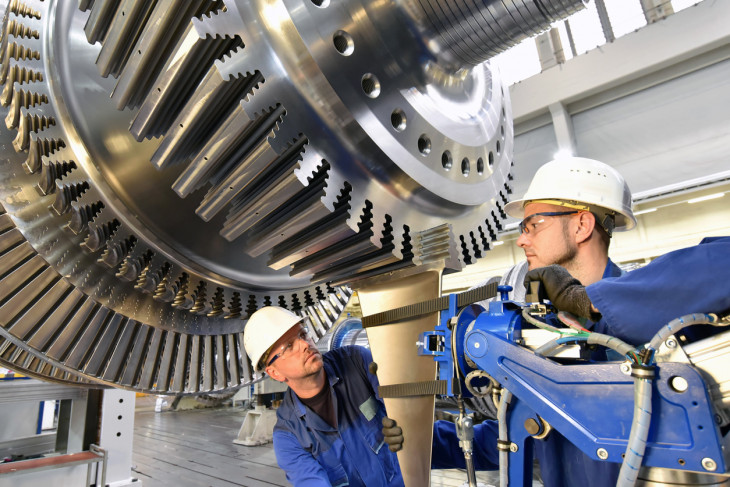 Workers assembling and constructing gas turbines in a modern industrial factory