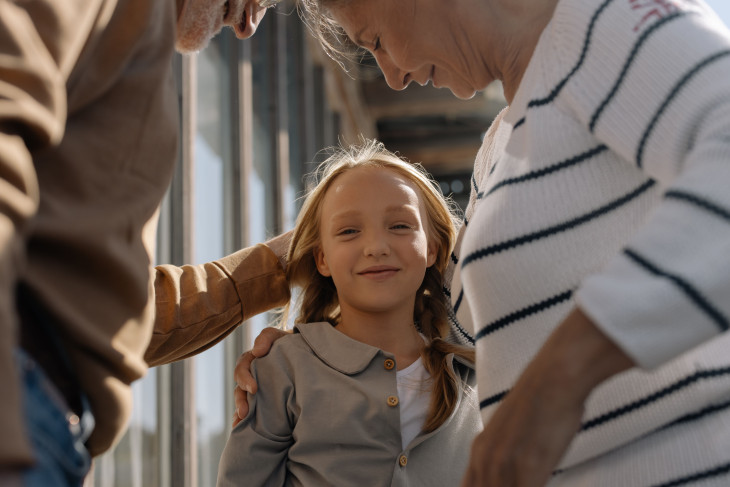 Girl smiling, accompanied by her grandparents