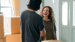 A young man and woman between moving boxes, laughing