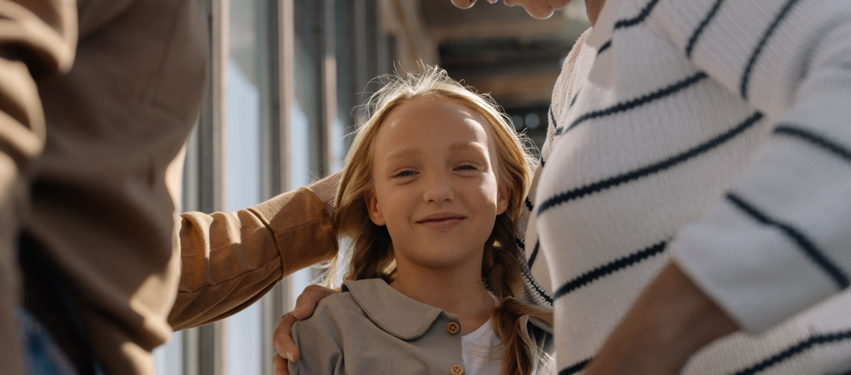Girl smiling, accompanied by her grandparents